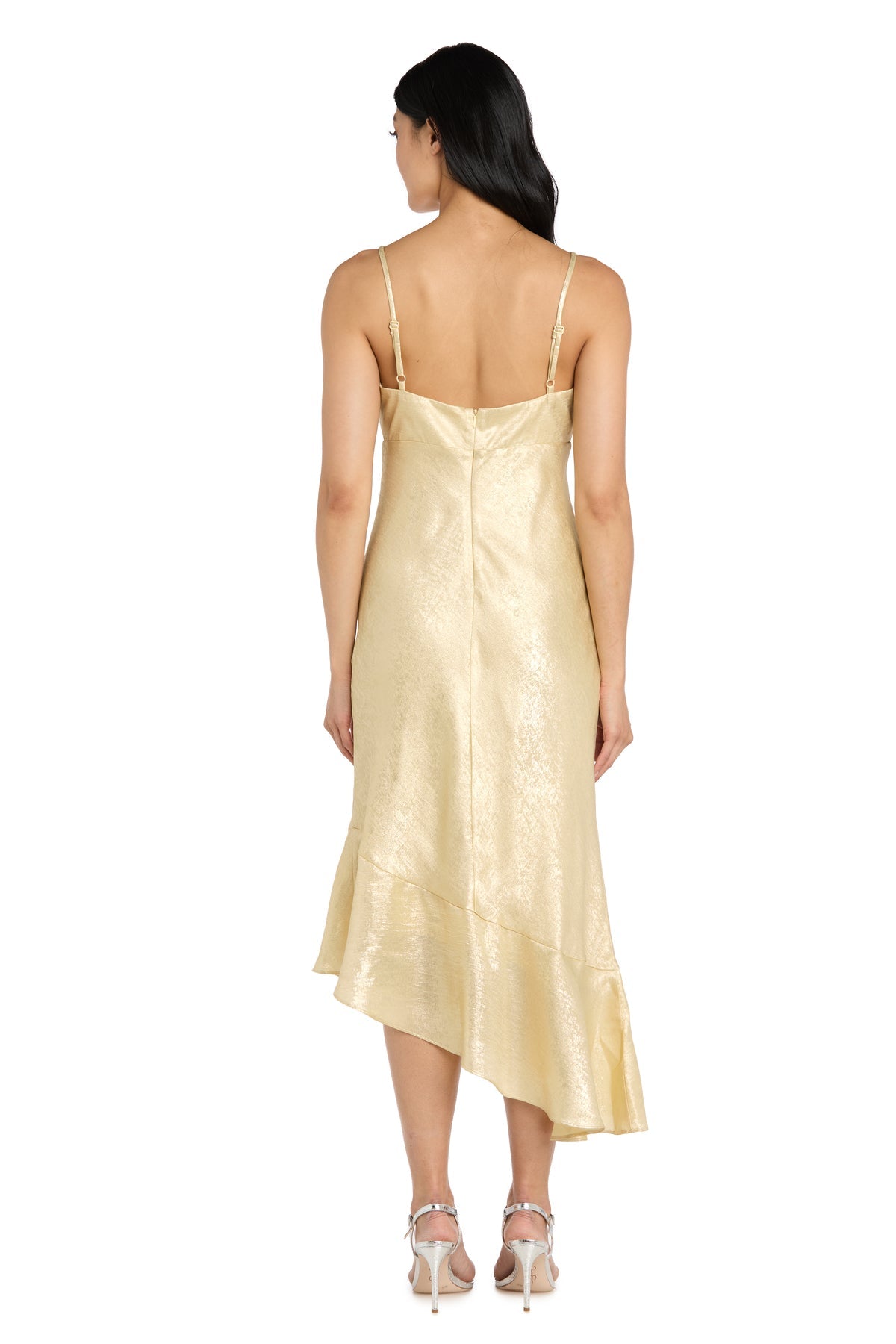 A woman faces away, wearing the Shimmer Midi Semi-Formal Dress: Morgan 10251, a gold shimmery dress with thin straps, an asymmetrical hem, and silver high-heeled sandals.