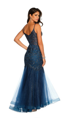 A woman in the Dave & Johnny A10625 Long Lace Mermaid Prom Dress, fitted and floor-length in navy blue with spaghetti straps, embroidered lace, and tulle accents, stands gracefully looking over her shoulder.