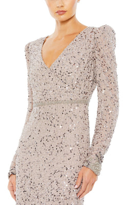 A woman wears the Mac Duggal 10740 Long Sleeve Wedding-Guest Dress, featuring a deep V-neckline, decorative cuffs, and shimmering sequin fabric shown from shoulders to thigh.