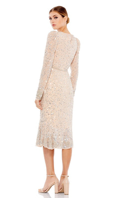 A woman faces backward, looking over her shoulder in the Mac Duggal 10740 long sleeve, light-colored sequin wedding guest dress, paired with nude high-heeled sandals.