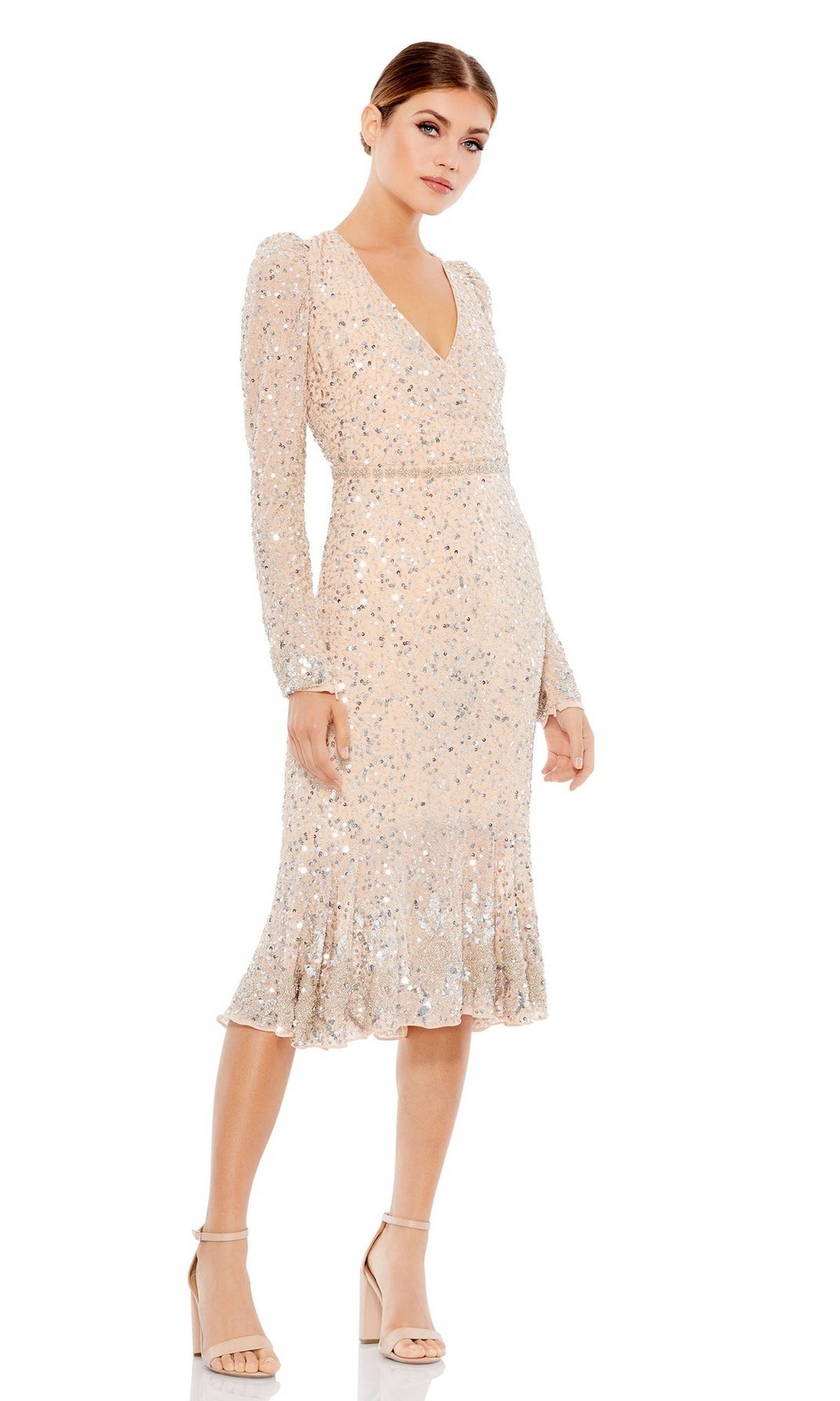 A woman wears the Mac Duggal 10740 Long Sleeve Wedding-Guest Dress, featuring sequins, a V-neckline, fitted waist, and ruffled hem. She completes the elegant look with nude high-heeled sandals.