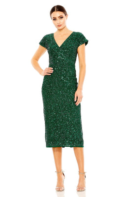 A woman stands in the Mac Duggal 10766 Midi Sequin Wedding Guest Dress with cap sleeves and shimmering sequins, paired with nude heels against a white background.