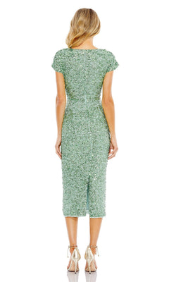 Woman faces away, wearing the fitted green Mac Duggal 10766 Midi Sequin Wedding Guest Dress with short sleeves and metallic high heels against a white background.