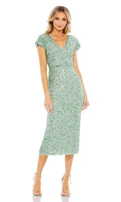 A woman wears the Mac Duggal 10766 Midi Sequin Wedding Guest Dress in light green with short sleeves, V-neckline, and sequins, paired with strappy heels, standing against a white background.