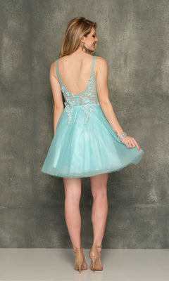 A woman in the Sheer-Bodice Short Homecoming Dress—light blue, a-line with floral appliques and a deep V back—stands against a gray textured background, facing away from the camera.