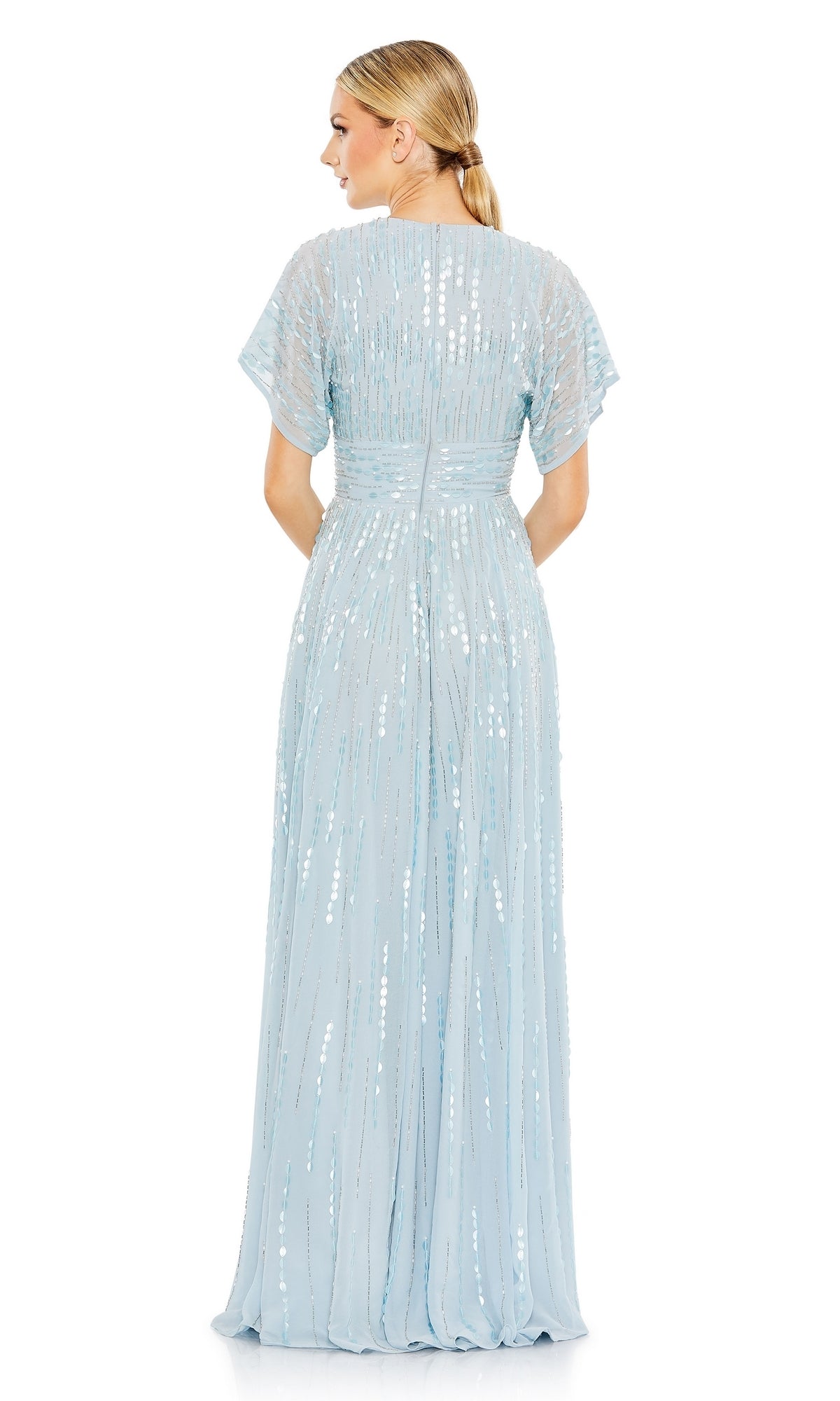 A woman wearing the Mac Duggal 10807 Short Sleeve Blue Formal Dress is shown from the back against a plain white background. This powder blue sequin A-line gown exudes elegance and timeless charm with its modest, formal design.