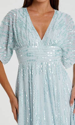 A woman wears the Mac Duggal 10807, a powder blue formal dress featuring short puff sleeves, a deep V-neckline, and shimmering sequins—an elegant choice for special occasions.