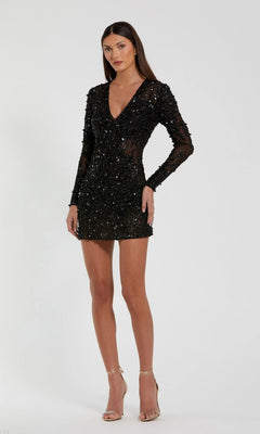 A woman poses against a plain background in the Mac Duggal 10976 black short cocktail dress featuring long sleeves, sequins, a deep V neckline, and strappy high heels.