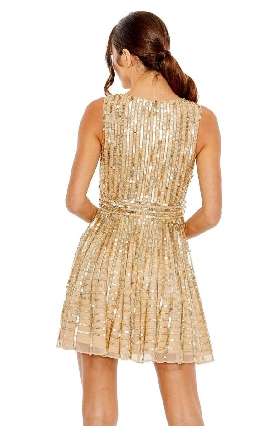 A woman stands with her back turned, wearing the Mac Duggal 10982 Short Gold Sequin Party Dress featuring vertical stripes and a fitted waist. Her hair is styled in a low ponytail.