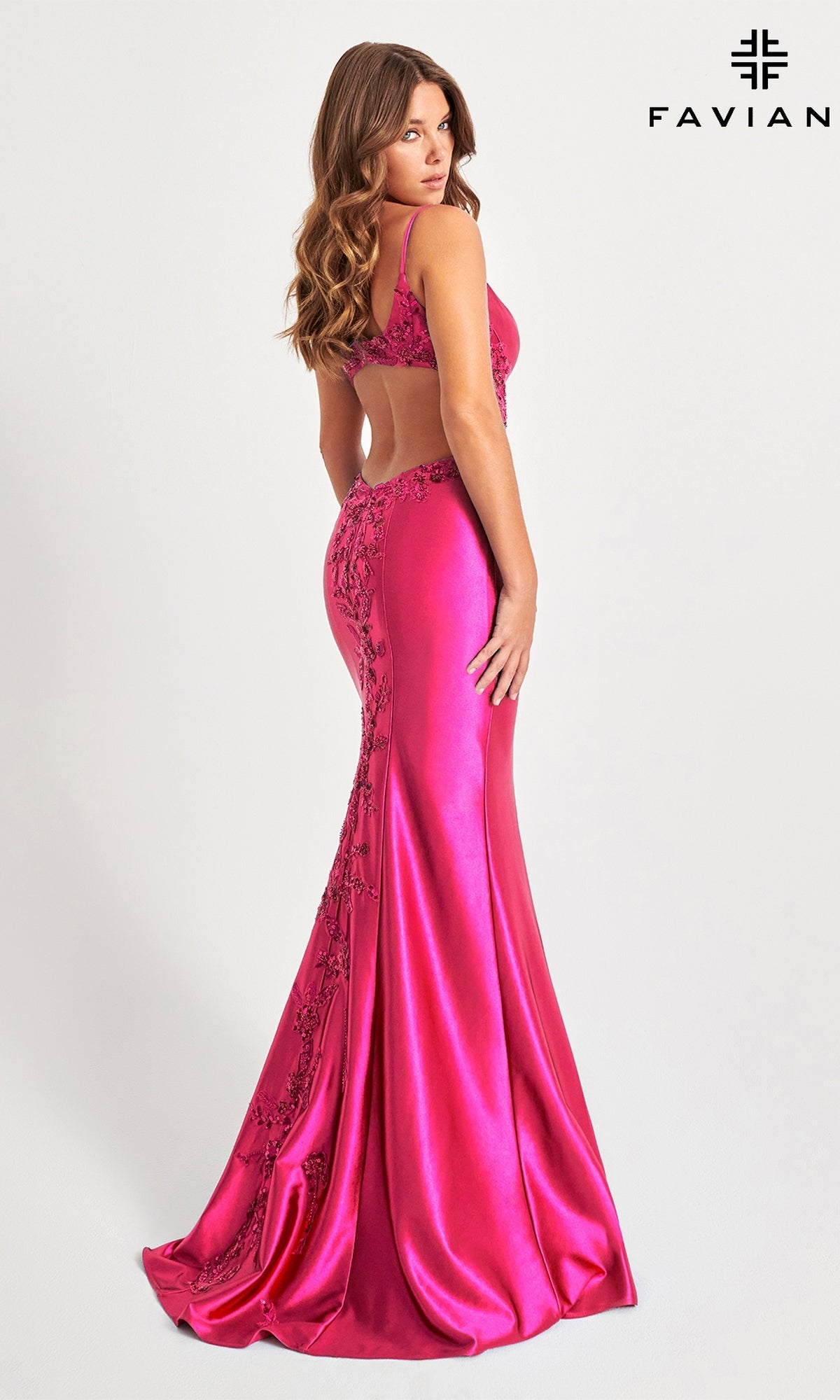 Woman in the Faviana Sheer-Lace Sides Long Prom Dress 11007—floor-length, bright pink, open-back with a mermaid skirt and floral details—stands looking over her shoulder. Faviana logo appears in the top right corner.