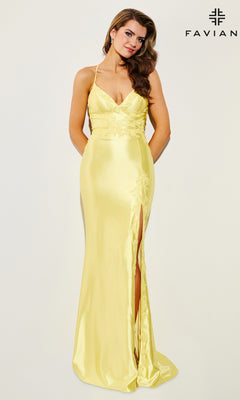 A woman models the Lace-Applique Faviana V-Neck Long Prom Dress 11010 featuring yellow satin, spaghetti straps, sequin lace appliqué, and a thigh-high slit, standing in front of a plain background with the Faviana logo.