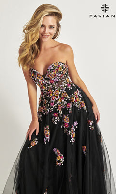 A woman models the Faviana Long Black Strapless Prom Dress 11028, featuring colorful floral embroidery, against a plain backdrop with the Faviana logo in the top right corner.