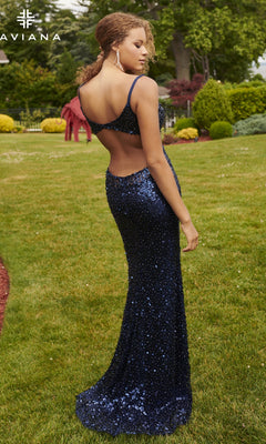 A woman wearing the Faviana Sheer-Sides Long Sequin Prom Dress 11032 in navy stands on grass, facing away in an outdoor garden setting.