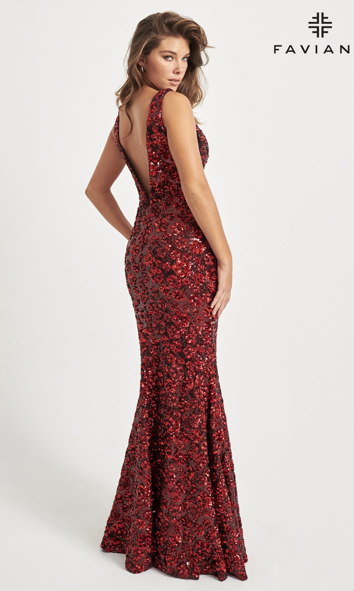 A woman stands before a white background in the Sequin-Floral Faviana Long Prom Dress 11038, a sleeveless, floor-length red gown with floral sequins and a low back. 