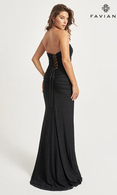 A woman in the Faviana Corset Long Strapless Prom Dress 11040, a floor-length black gown with a lace-up back and elegant beaded details, stands sideways and glances over her shoulder, showcasing its sparkling embellishments.