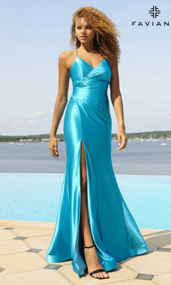 Wearing the Faviana Lace-Up Long Satin Prom Dress 11051 in bright blue, a woman stands by a pool. This elegant gown features thin straps, a wrapped bodice, and a thigh-high slit with water and trees behind her.