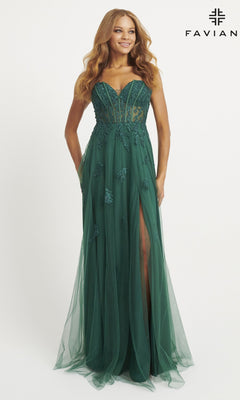 A woman models the Strapless Tulle Faviana Long Prom Dress 11057 in deep green, featuring a sheer corset bodice, floral appliqués, a high front slit, and a floor-length tulle skirt, standing against a plain white background.