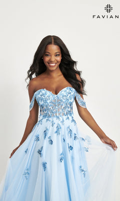 A woman models the Faviana Off-Shoulder Long A-Line Prom Dress 11059 in light blue, featuring floral appliqués and a sheer corset bodice. She poses against a plain white background with the FAVIAN logo in the top right corner.
