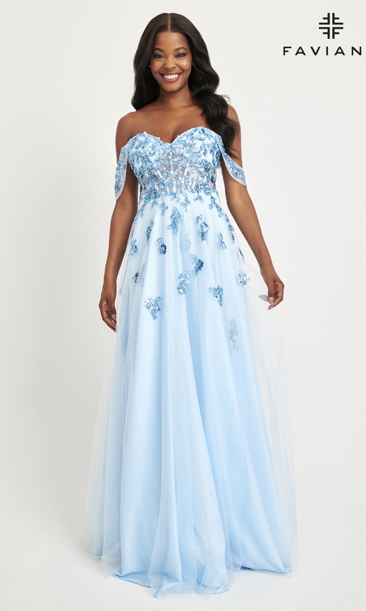 A woman smiles against a white background wearing the Faviana Off-Shoulder Long A-Line Prom Dress 11059 in light blue, featuring floral appliqué details and a sheer corset bodice.