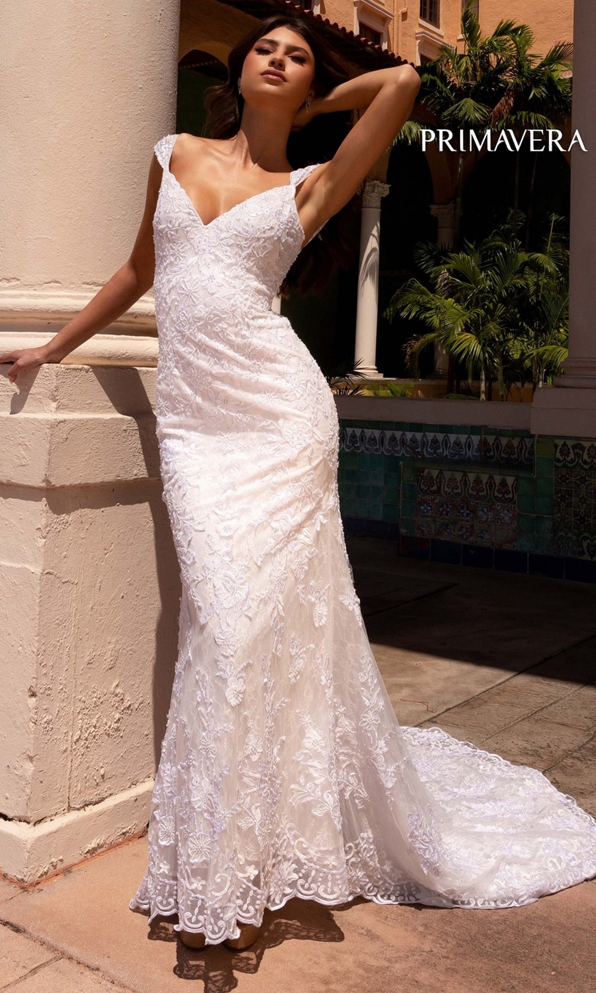 A woman stands outdoors in the Long Wedding Dress 11107 by Primavera, featuring an ivory hue, fitted bodice, flared skirt, and delicate lace. 