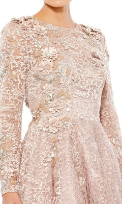 A person wearing the Mac Duggal 11121 Long Sleeve Mocha Formal Gown featuring elegant lace, floral appliqué, and intricate embroidery.