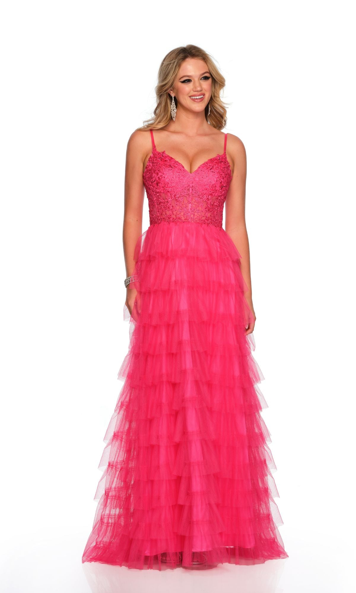 A woman wears the Dave and Johnny Long Tiered Prom Dress 11148, featuring a bright pink lace v-neck, fitted bodice, and layered tulle skirt, standing against a white background.