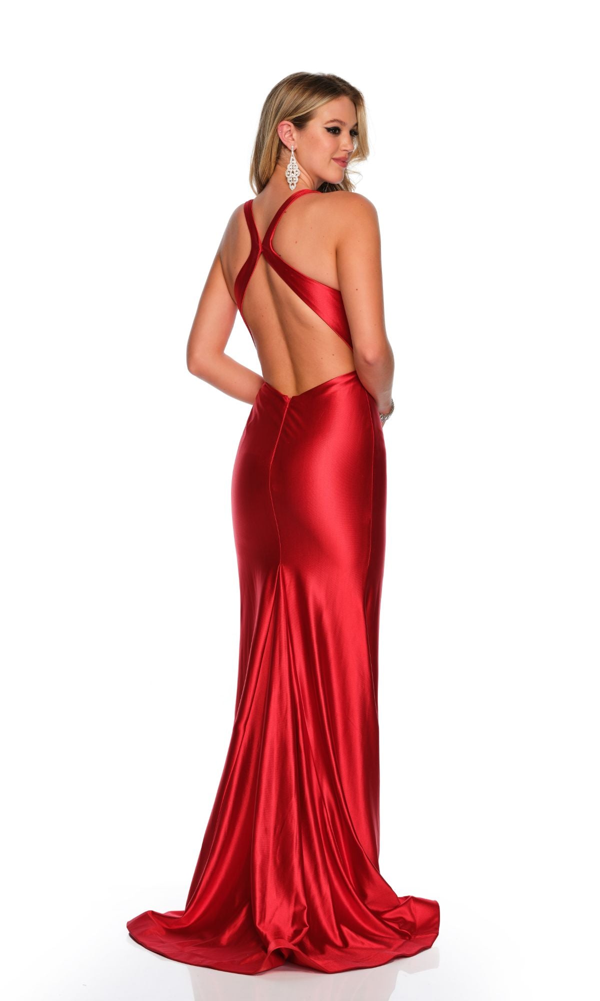 A woman models the Dave and Johnny Long Red Prom Dress 11157, featuring a floor-length design and crisscross open back, as she poses facing away from the camera against a white background.