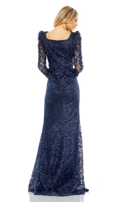A woman models the Mac Duggal 11187, a long sleeve navy blue lace formal gown, facing away to showcase the elegant back details of this floor-length mother of the bride dress.