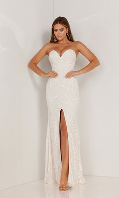 A woman poses against a white wall wearing the Aleta Long Prom Dress 1118, a strapless gown with a sweetheart neckline, beaded sequin detailing, and a front slit. She pairs the look with long hair and hoop earrings.