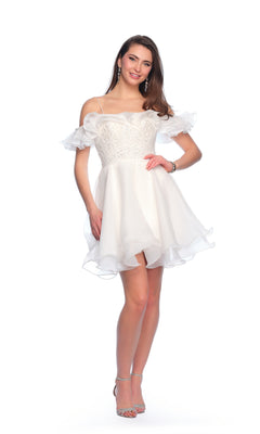 A woman stands and smiles, wearing the Short Ivory Ruffle Hoco Dress 11201 with ruffled sleeves and clear high-heeled sandals, posing against a white background.
