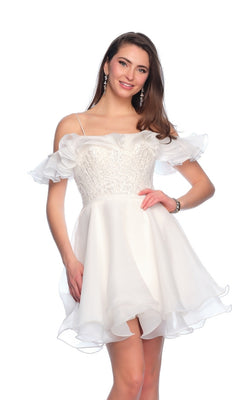 A woman stands smiling against a white background in the Short Ivory Ruffle Hoco Dress 11201, featuring an off-shoulder design, ruffled sleeves, sequin bodice, and flared skirt.