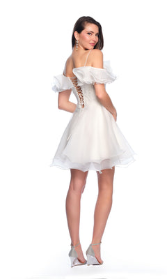Woman in the Short Ivory Ruffle Hoco Dress 11201, featuring off-the-shoulder ruffled sleeves and a lace-up back, poses in high heels against a white background.