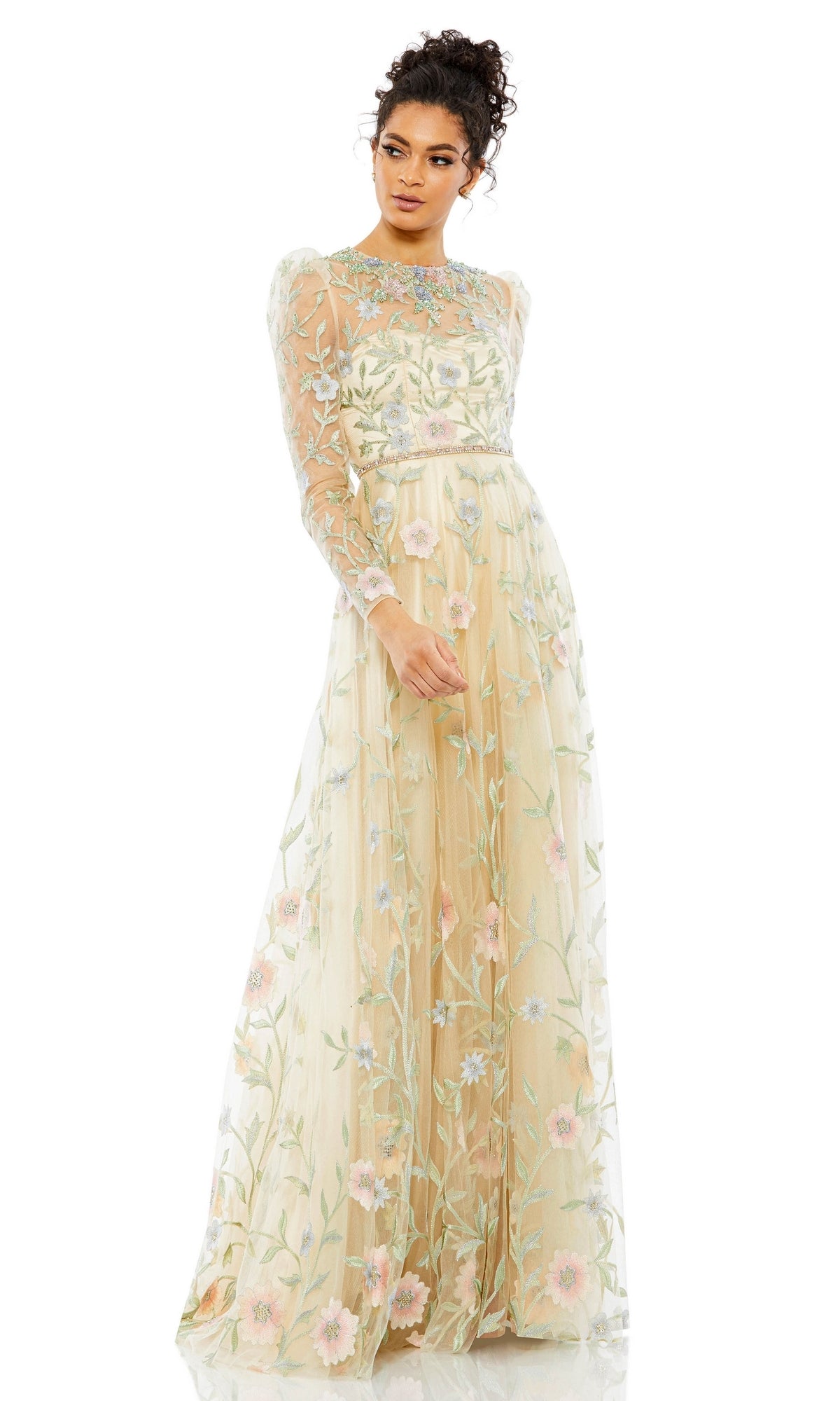 A woman stands against a white background wearing the Long Formal Dress 11226 by Mac Duggal, featuring sheer fabric, floral embroidery, long sleeves, and a high neckline.