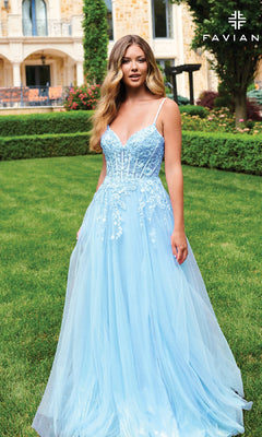 A woman stands on a manicured lawn before an elegant building, wearing the Faviana 11230—a long, light blue A-line prom dress with a lace bodice, fitted corset top, tulle skirt, and delicate floral applique.