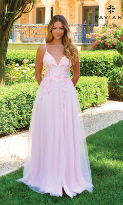 Outdoors in a garden, a woman wears the Faviana 11232 Long Pastel A-Line Prom Dress with floral embroidery, a flowing light pink tulle skirt, and a delicate v-neckline for an elegant look.