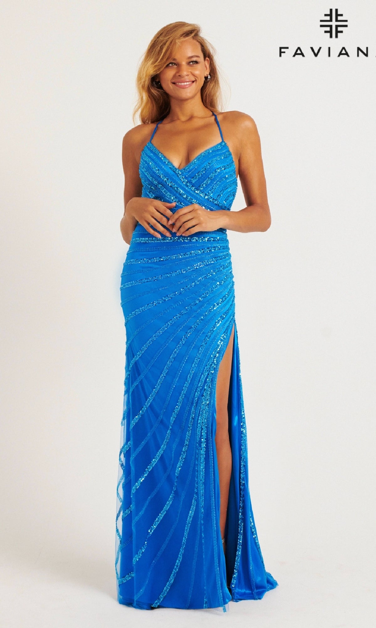 A woman poses against a plain white background wearing the Faviana 11242 long prom dress, featuring bright blue sequins, a v-neckline, and a high leg slit. 
