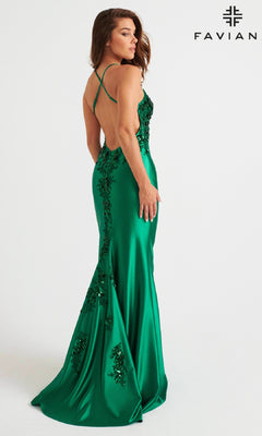 A woman wears the Faviana 11247, a floor-length green prom dress with sequins, an open back, and stretch satin fabric, posing before a white background with the Faviana logo.