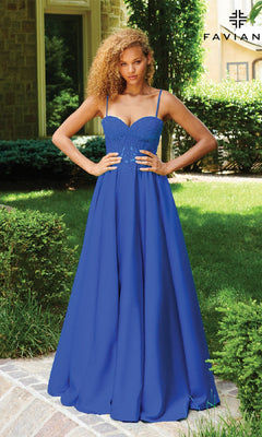 A woman stands outdoors in the Faviana 11259 Lace-Up Long A-Line Prom Dress, a blue gown with thin straps and an embroidered lace corset bodice featuring delicate detailing.
