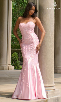 A woman stands outdoors in the Faviana 11271 long prom dress, a strapless mermaid gown with light pink lace and floral embroidery that accentuate its elegant silhouette.