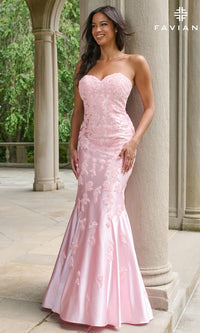 A woman poses outdoors near stone columns and greenery wearing the Faviana 11271 long prom dress, a strapless mermaid gown in light pink with embroidered details.
