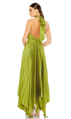 A woman stands with her back to the camera, wearing the Long Formal Dress 11302 by Mac Duggal—a shiny green pleated halter gown featuring an asymmetrical hemline.
