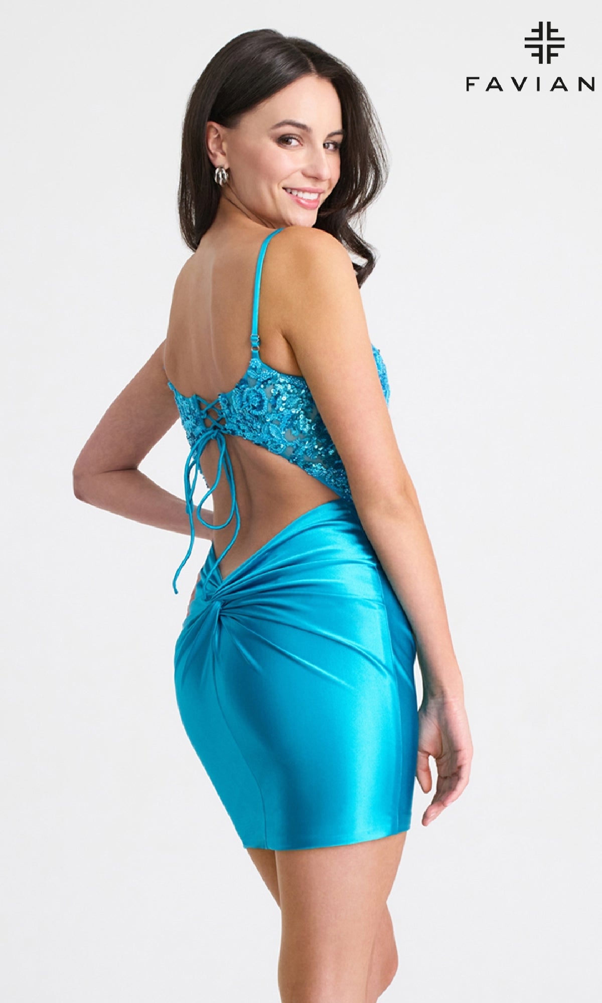 A woman poses in a bright blue, fitted satin cocktail dress with an open twist-back, looking over her shoulder. The product name 