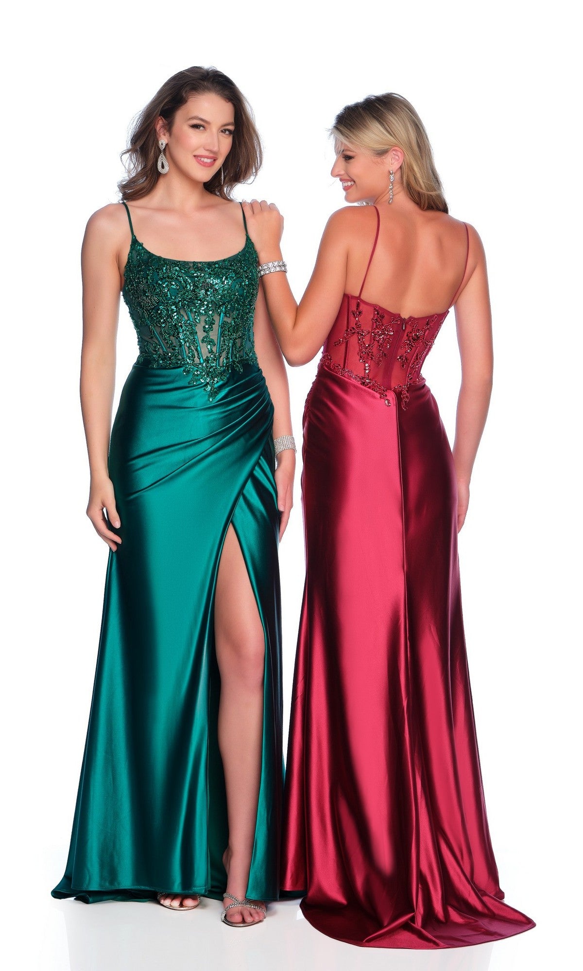 Two women pose and smile in elegant long prom dresses against a white background: one wears a green satin gown with thigh slit and sheer bodice, the other dons the Sheer-Bodice Long Prom Dress: Dave & Johnny 11330, a red low-back style.