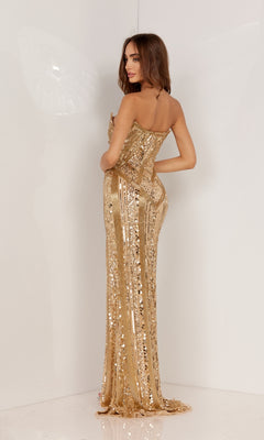 A woman stands in a plain white setting, looking over her shoulder and wearing the Strapless Beaded Long Formal Dress 1135, featuring gold sequin geometric designs.