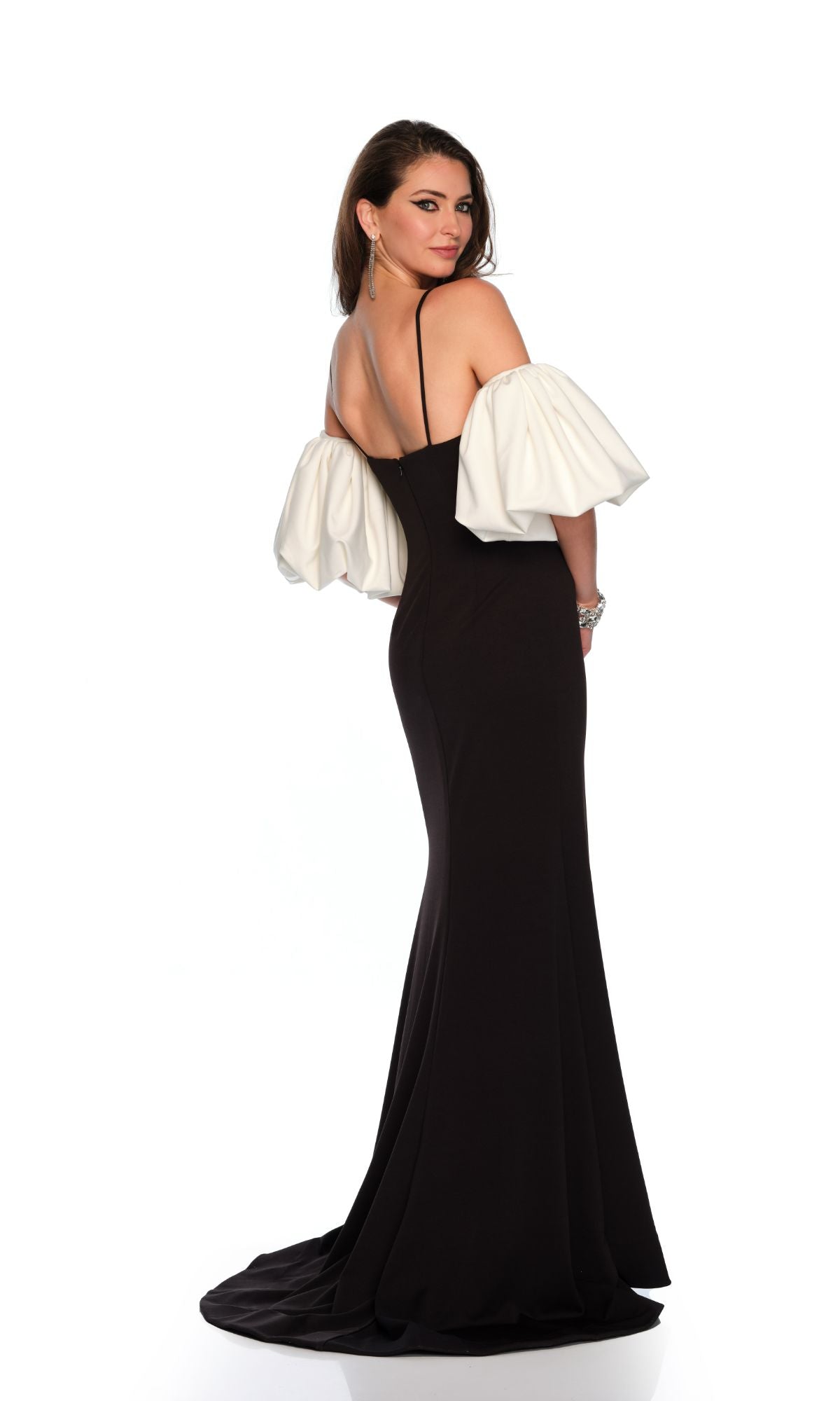 A woman models the Long Formal Dress 11368 by Dave and Johnny—a fitted black gown with white puff sleeves—while standing and looking over her shoulder against a white background.