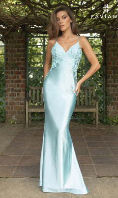 A woman poses outdoors in the Faviana 11402 long prom dress, featuring light blue satin, a v-neckline, and floral lace applique bodice, with one hand in her pocket against a brick and wooden pergola backdrop.