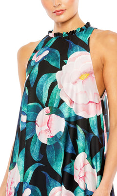 A woman wears the Mac Duggal 11406 Floral-Print Long Formal Dress, a sleeveless, high-neck gown with ruffles and bold pink flowers with green leaves on a black background.