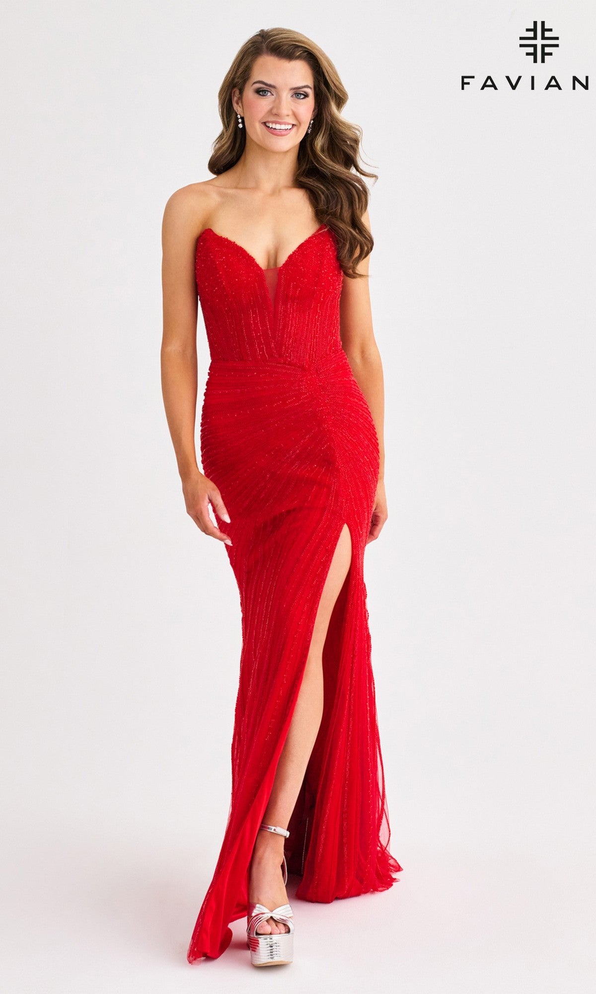 A woman models the Faviana 11410 Long Prom Dress—strapless, form-fitting, red with a thigh-high slit—paired with silver platform heels. She stands before a plain background with 