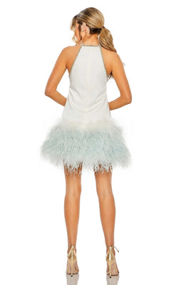A woman faces away, her hair in a ponytail, wearing the Short Homecoming Dress 11437 by Mac Duggal—a sleeveless dress with a white feathered skirt and metallic high heels.