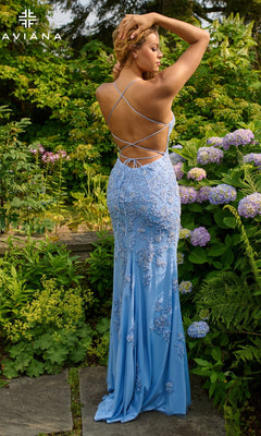 A woman stands in a garden wearing Faviana 11440, a light blue long prom dress with an open back, strappy details, and beaded applique, surrounded by green foliage and blooming hydrangeas.